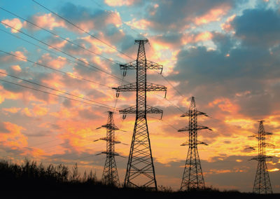 High voltage power transmission line. Silhouette electricity post on sunset background